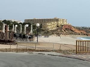plaża ze stołami i krzesłami oraz budynek w obiekcie Mirador De Aguamarina w mieście Campoamor