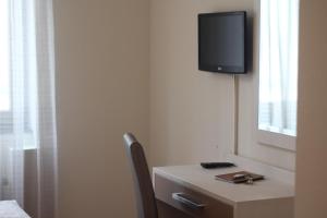 a room with a desk with a tv on the wall at Hotel Centro in Stuttgart