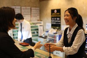 Uma mulher a entregar um cartão de crédito a outra mulher numa loja. em Hotel New Yokosuka em Yokosuka