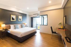 a bedroom with a bed and a desk and a television at Alt Hotel Nana by UHG in Bangkok