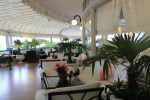 un hall avec des chaises et des plantes en pot dans un bâtiment dans l'établissement Hotel Corallo, à Bibione