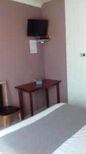 a bedroom with a bed and a desk with a television at Hotel le Bon Soleil in Les Sables-d'Olonne