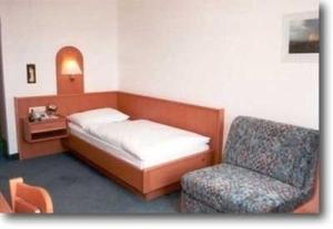 ein kleines Schlafzimmer mit einem Bett und einem Stuhl in der Unterkunft Gasthof Zur Linde in Neuhofen an der Ybbs