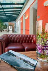 a lobby with a couch and a vase of flowers on a table at Hotel Caesar Prague in Prague