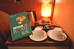 un libro e due tazze e piattini su un tavolo di Hotel Carmel a Roma