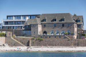 een groot gebouw aan het strand naast het water bij Relais & Châteaux Le Brittany & Spa in Roscoff