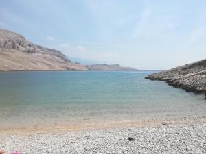 a beach with blue water and mountains in the background at LARA & VITO in Metajna