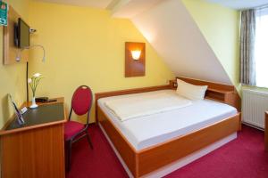 a bedroom with a bed and a desk and a chair at Hotel garni Harzer Hof in Osterode