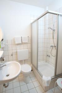 a bathroom with a shower and a toilet and a sink at Hotel garni Harzer Hof in Osterode