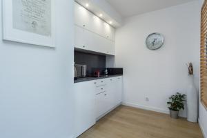 グダニスクにあるElite Apartments Chmielna Deluxeの白いキャビネットと壁掛け時計付きのキッチン