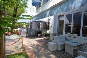 un patio exterior de un edificio con muebles blancos en Hotel Villa Erica, en Grado