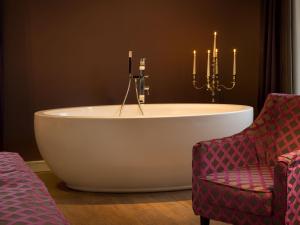 a bathroom with a tub and a chair and candles at Boardinghouse Rathsmühle in Aachen