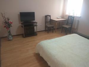 a bedroom with a bed and a tv and chairs at Hotel Andreevsky in Vinnytsya