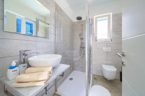 a white bathroom with a sink and a shower at Apartments Mali Nono in Krk
