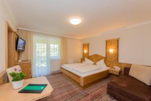 a hotel room with a bed and a couch at Landhotel Oberdanner in Saalbach-Hinterglemm