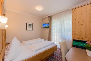 a bedroom with a bed and a table and a window at Landhotel Oberdanner in Saalbach Hinterglemm