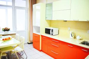 a kitchen with orange cabinets and a table with a microwave at Luxury Palace Apartment in Bishkek