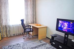 una habitación con un escritorio y una silla y un televisor en Luxury Palace Apartment, en Bishkek
