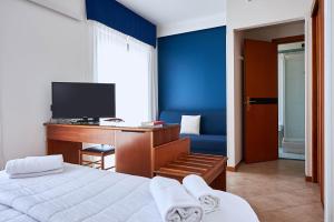 a bedroom with a bed and a desk with a television at Hotel Croce Di Malta in Imperia