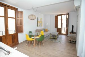 sala de estar con mesa y sillas amarillas en Feelathome Mártires Apartments, en Málaga