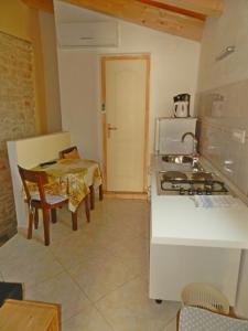 Il comprend une cuisine équipée d'une cuisinière et d'une table. dans l'établissement Apartment Pokrajac, à Rovinjsko Selo
