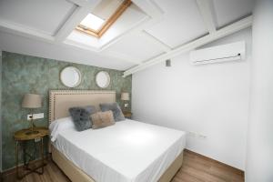 a bedroom with a white bed and two mirrors at Feelathome Mártires Apartments in Málaga