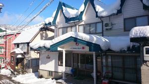 une maison avec de la neige sur le toit dans l'établissement Nozawa Dream, à Nozawa Onsen