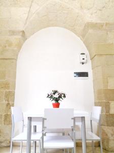 a white table with white chairs and a vase with flowers at CASA TIPICA indipendente in Carpignano Salentino