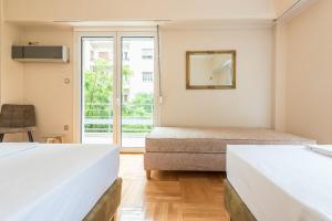 1 Schlafzimmer mit 2 Betten, einem Spiegel und einem Fenster in der Unterkunft Victoria Familia Apartments in Athen