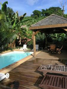 a wooden deck next to a swimming pool with a gazebo at Villa Maora in Kangani