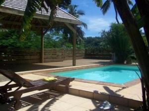 a swimming pool with a chair and a house at Villa Maora in Kangani