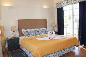 Quinta dos Oliveiras في كارفويرو: غرفة نوم مع اثنين من مناشف البجع على سرير