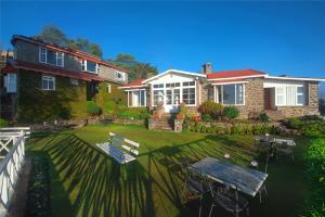 a house with a yard with a table and benches at Villa Retreat - Boutique Hotel in Kodaikānāl