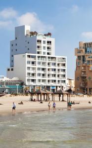 un groupe de personnes sur une plage avec un bâtiment dans l'établissement Sea Executive Suites, à Tel Aviv