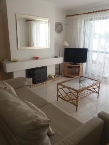 a living room with a couch and a tv at A Apartmento Solar dos Pinheiros in Vilamoura