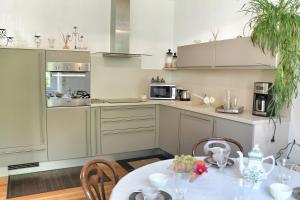 eine Küche mit einem Tisch, Stühlen und einer Mikrowelle in der Unterkunft La Maison des Fontaines d'Alsace in Ferrette