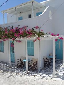 un edificio bianco con tavoli, sedie e fiori rosa di Galanis Place a Città di Antiparo