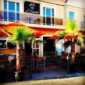 un restaurant avec des tables, des chaises et des parasols dans l'établissement Hotel Restaurant L'Escale, au Grau-dʼAgde