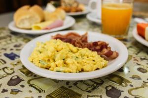 a plate of scrambled eggs and bacon and a glass of orange juice at Sadas Hotel in São Mateus do Sul