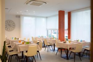 a restaurant with white tables and chairs and a clock at Hotel Casa Costiera in Caorle