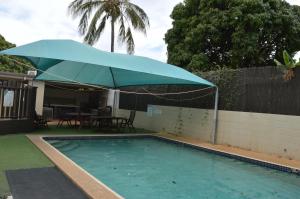a swimming pool with a blue umbrella over it at Mid City Motor Inn in Gladstone