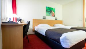 a hotel room with two beds and a desk at Bastion Hotel Heerlen in Heerlen