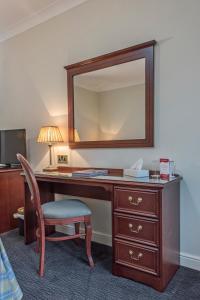 a bedroom with a dresser, chair, mirror and a lamp at Ben Nevis Hotel & Leisure Club in Fort William