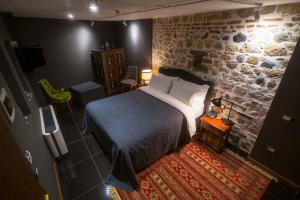 um quarto com uma cama e uma parede de pedra em HANI I PAZARIT Boutique Hotel em Korçë