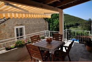 a patio with a table and chairs on a balcony at Mediterranean stone house in Babino Polje