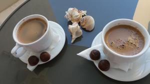 two cups of coffee sitting on a table withocolates at Frontal view by Twin Residence in Mamaia