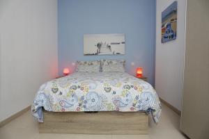 een slaapkamer met een bed met een kleurrijk dekbed bij Apartamento Playa Las Canteras in Las Palmas de Gran Canaria