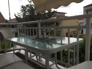 a glass table on a balcony with chairs at Phaethon Apartments & Studios in Kallithea Halkidikis