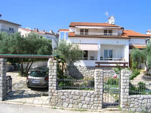a house with a stone wall and a car parked in front at Apartments Oribella in Krk