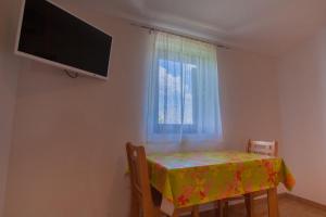 a room with a table and a television and a window at Apartments Dandić in Orlec